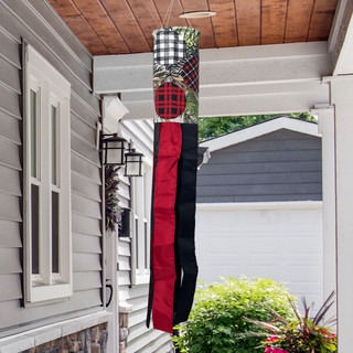 Patterned Ornaments Windsock Wind Twister hanging from a porch, featuring red, black, and plaid designs.