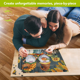 Couple working on Briarwood Lane Fall Gnomes 1000-piece jigsaw puzzle with autumn gnomes on wood.