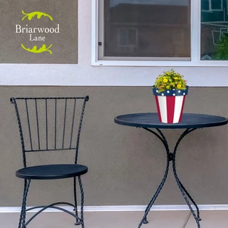 Briarwood Lane American Flag Small Planter on a black table with yellow flowers.