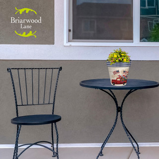 Briarwood Lane Stars and Stripes Truck Small Planter with flowers on outdoor table and chair.