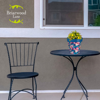 Briarwood Lane Abstract Floral Small Planter with yellow flowers on a black metal table and chair.