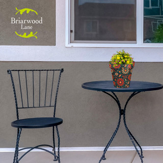Small black metal chair and table with Briarwood Lane floral planter on patio setting outdoors.