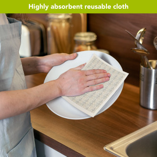 Flowing Leaves Swedish Dishcloth, beige kitchen cloth drying white plate on wooden countertop with hands.