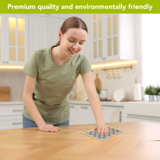 Woman using pink and blue check Swedish dishcloth on wooden table in modern kitchen setting.