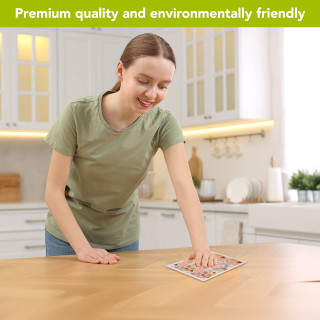 Woman using Colorful Flowers Swedish Dishcloth in a kitchen, wiping wooden table surface clean.