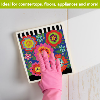 Bright Blooms Swedish Dishcloth with colorful floral design on a white surface with a hand.