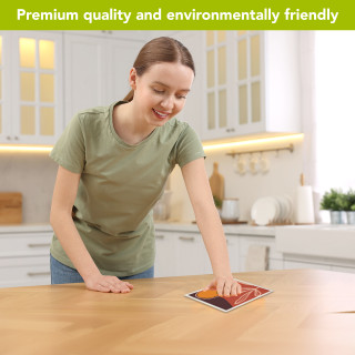 Woman wiping wooden table with vibrant orange and brown Desert Swedish Dishcloth in a kitchen.