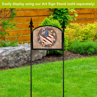 Americana Barnstar Acrylic Art Sign with American flag design on a decorative black metal stand outdoors.