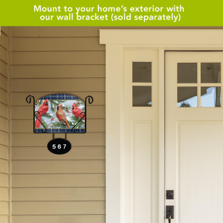 Wintertime Cardinals Acrylic Art Sign with cardinals, hung on beige siding next to a white door.