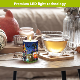Halloween gnome flameless candle with LED light on a table with tea and pumpkins nearby.