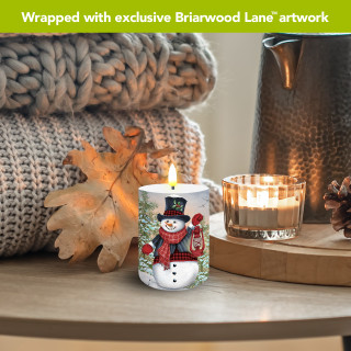 Snowman and Friends Flameless Candle, white candle with snowman design, lit candle on wooden table.