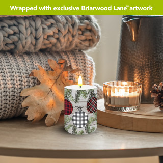 Patterned Ornaments Flameless Candle, white with green pine and plaid ornament designs, lit on table.