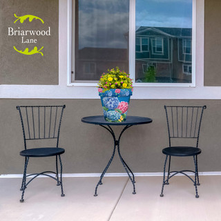 Colorful Hydrangeas Medium Planter on a small black table between two black metal chairs outside.