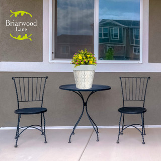 Flowing Leaves Medium Planter with yellow flowers on a small black outdoor table and chairs.
