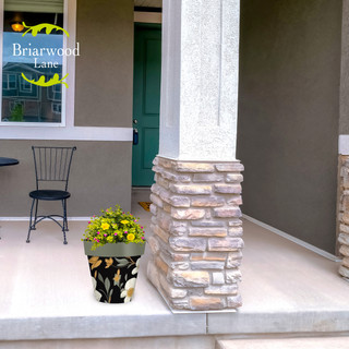 Elegant Flowers Medium Planter with yellow blooms on a porch next to a pillar and chair.
