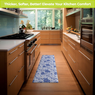 Blue and white oversized floral comfort mat in a kitchen with wooden cabinets and floors.