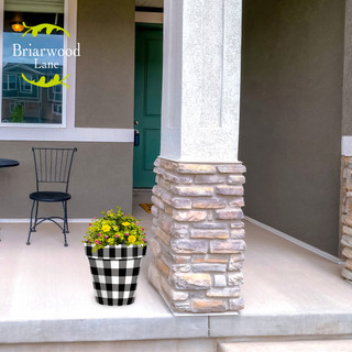 Black and white buffalo check medium planter with yellow flowers on a front porch.