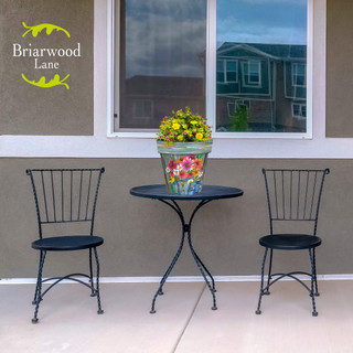 Farm Fresh Flowers Medium Planter with yellow blooms on a small outdoor table between two chairs.