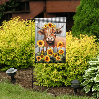 Highland Cow Garden Flag with brown cow, sunflowers, and floral crown on a black metal stand outdoors.