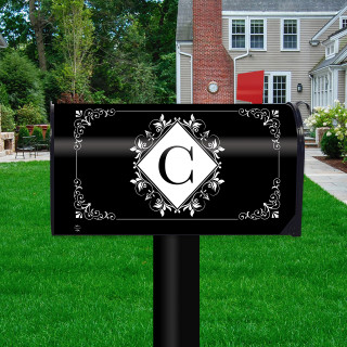 Black and white monogram mailbox cover with floral design and letter C on a post outdoors.