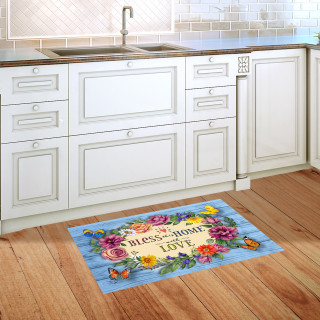 Bless This Home With Love doormat on wooden floor in front of white kitchen cabinets.