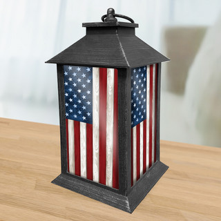 Black metal lantern with American flag design on sides, wooden base on table top.