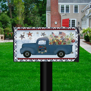 Blue pickup truck mailbox cover with patriotic design and stars, flowers, on a lawn post outdoors.