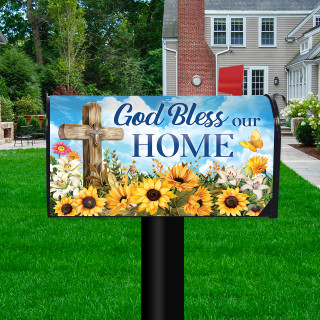 God Bless Our Home mailbox cover with cross, sunflowers, and flowers on a black post outdoors.