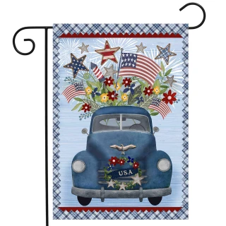 Blue vintage pickup truck with USA license plate and patriotic flowers on Celebrate America garden flag.