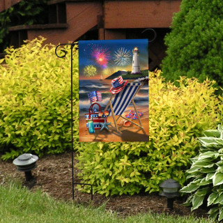 Oceanside Fireworks Garden Flag with beach scene, lighthouse, fireworks, and American flags on display outdoors.