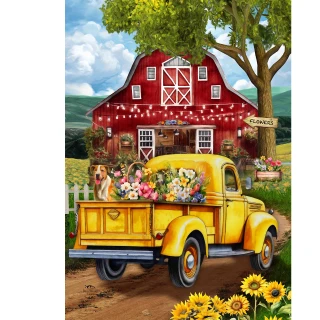 Yellow vintage truck with flowers and dog, parked in front of red barn with white trim.