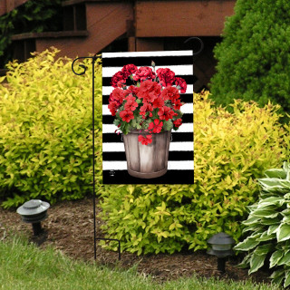 Striped garden flag with red geraniums in a metal pot on black and white background.