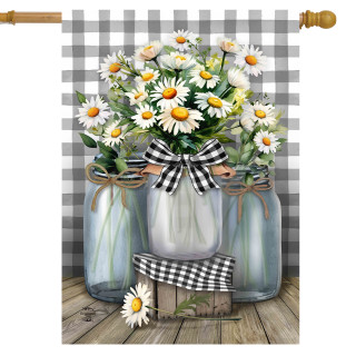 Three mason jars with daisies and black and white ribbons on a wooden surface and background.
