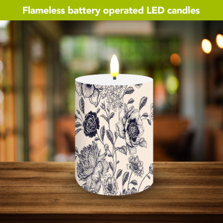 Woodcut Floral battery operated LED candle with black floral design on white background lit.