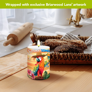 Sunset Parrot Flameless Candle with colorful parrot design on a wooden table with baked goods.