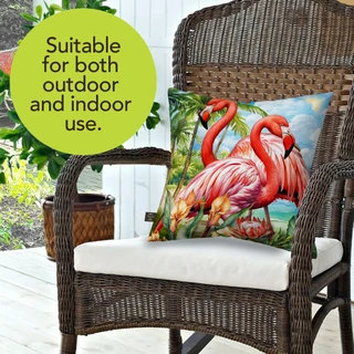 Flamingo Pair Indoor/Outdoor Pillow on a wicker chair with vibrant pink flamingos and tropical design.