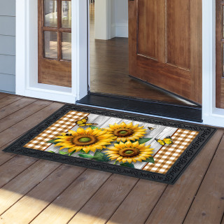 Sunflower Duo Doormat with yellow sunflowers and checkered pattern on a wooden porch outside doorway.