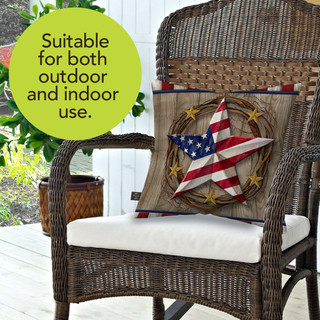 American Barn Star Indoor/Outdoor Pillow on a wicker chair with white cushion and American star design.