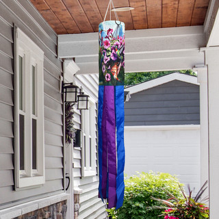 Hummingbirds and Petunias Windsock Wind Twister hanging from a porch, vibrant purple and blue hues.