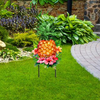 Pineapple and Stripes Metal Art garden decoration with pink flowers on green lawn with stone pathway.