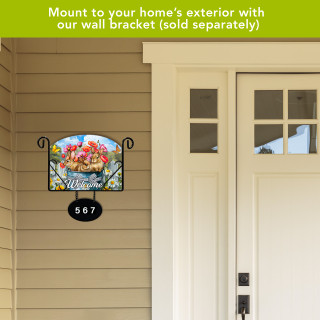 Bucket of Bunnies colorful acrylic art sign with house number on tan siding exterior wall.