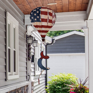 American burlap hot air balloon spinner with tea stained design on metal pole outdoors.