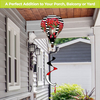 Red and black striped geranium hot air balloon spinner on a pole outdoors near a house.