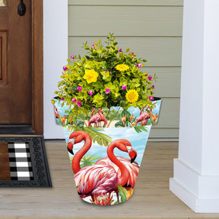 Large planter with flamingo design, filled with green plants and colorful flowers on a porch.