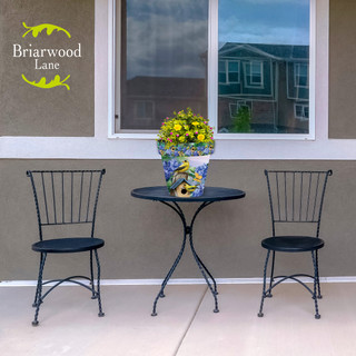 Briarwood Lane Goldfinches and Hydrangea medium planter on black metal table between two chairs.