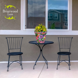 Zinnias in Bloom medium planter on black outdoor table between two black metal chairs outside.