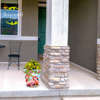 Briarwood Lane Flamingo Pair Medium Planter with yellow flowers on a home's porch area.