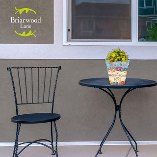 Briarwood Lane Bless This Home With Love small planter with yellow flowers on a black table.
