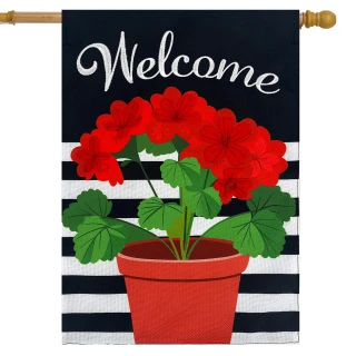 Red geraniums in red pot on black and white striped house flag with welcome text.