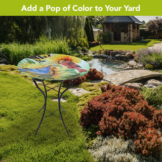 Birds in the Garden Glass Birdbath with vibrant bird design on a stand in a garden setting.